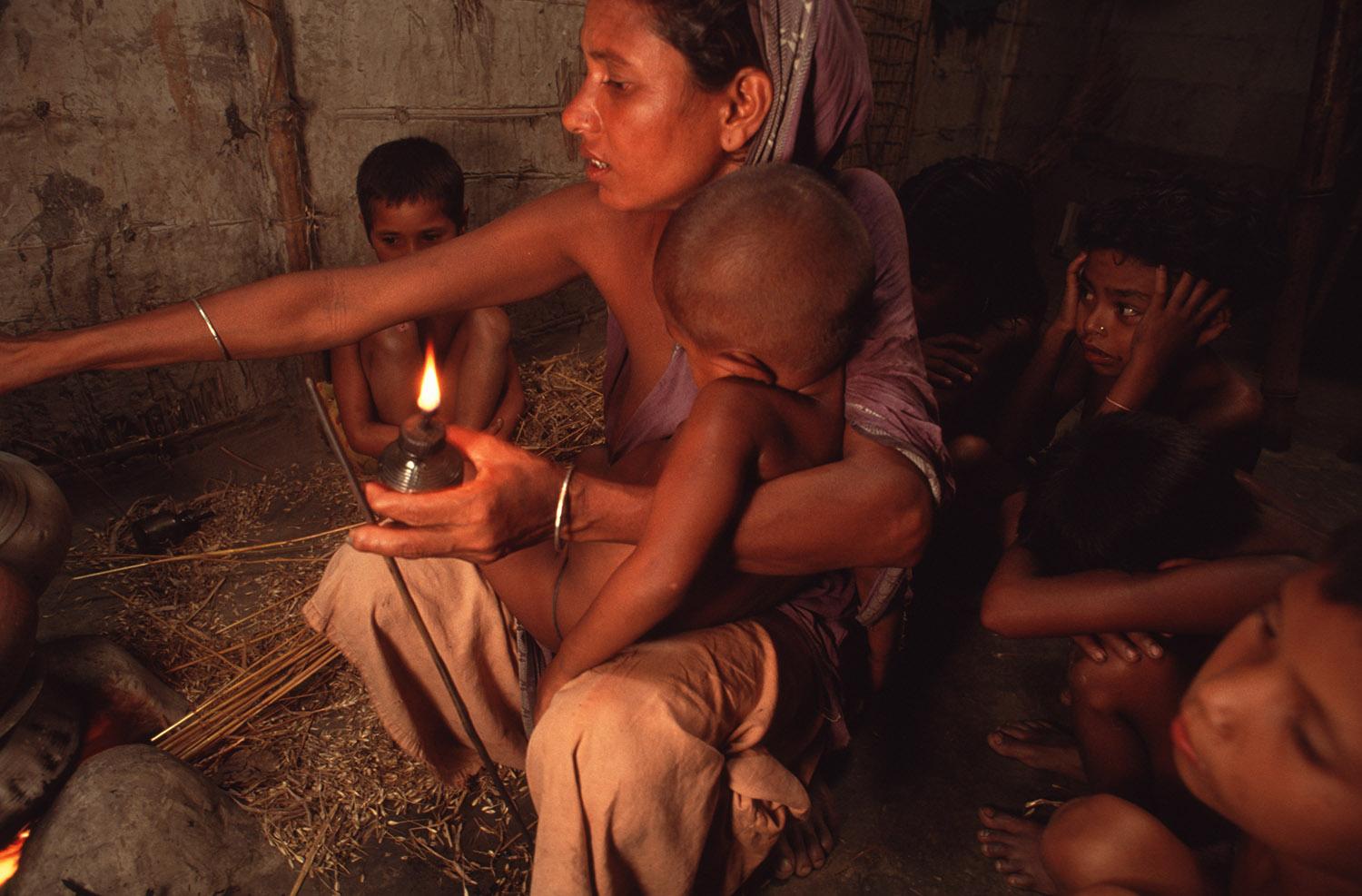 A widow cooks dinner for her many children in her one-room house. This is the main and often only meal of the day for this impoverished family.