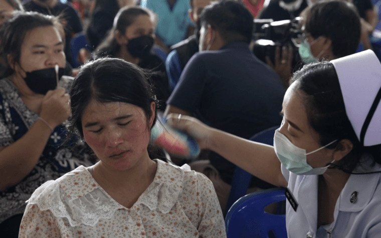 A nurse fans a woman who appears to be in shock as she grieves for her child who was among 24 childen killed by Panya Khamrab at a child care center in northeast Thailand. Photo by Yvan Cohen