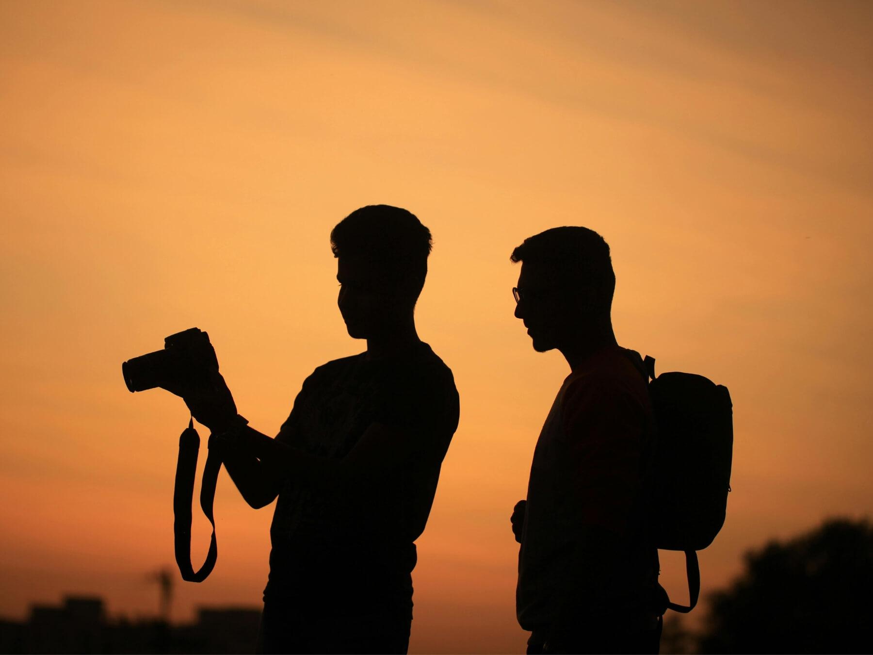 Silhouette of man holding a camera with a tripod 