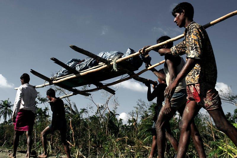 Survivors carry a victim of cyclone Sidr. Sidr prompted one of the worst natural disasters in Bangladesh. At least 3,447 deaths were attributed to the cyclone, with some estimates as high as 15,000.