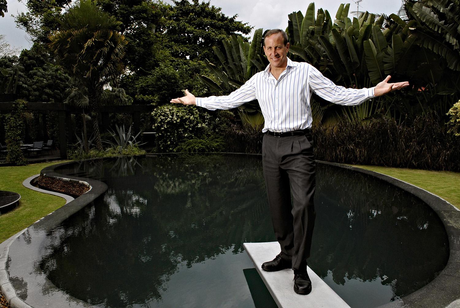 Bill Bensley, a landscape architect and resort planner, poses on a swimming pool diving board in the gardens of his Bangkok headquarters, Bensley Design Studios.