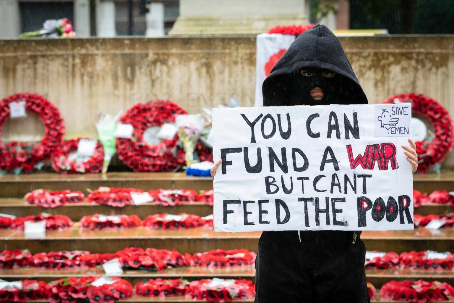 A demonstrator holds a placard in front of the Cenotaph. Several demonstrations were seen in close proximity to each other including Black Lives Matter and Anti-War movements coming together despite a global pandemic being in place due to COVID-19. Manchester, UK July 04, 2020. Credit: Andy Barton