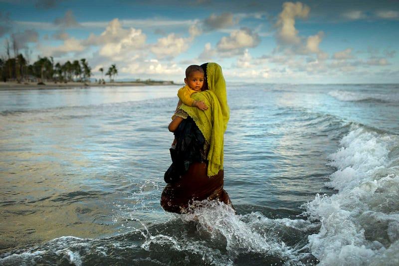 Myanmar Rohingya refugee woman hold her son seen after arriving on a boat to Bangladesh on Shah Porir Dip Island. Story and photo credits by K M Asad