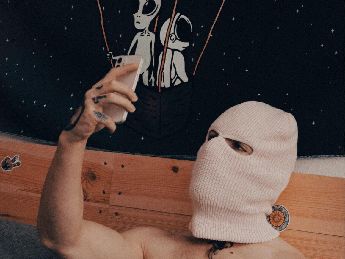 A masked man taking a selfie.