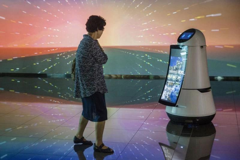 An old woman is looking at a guide robot which is on display at Incheon International Airport in Seoul / South Korea.